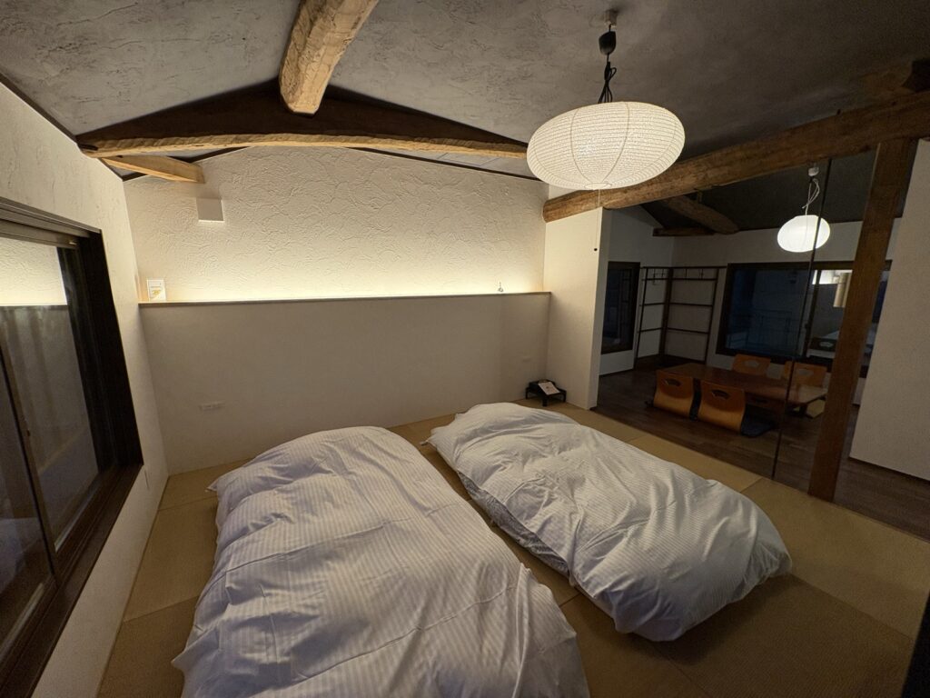 客室ほたるの間。畳に敷かれた布団と古民家の梁
