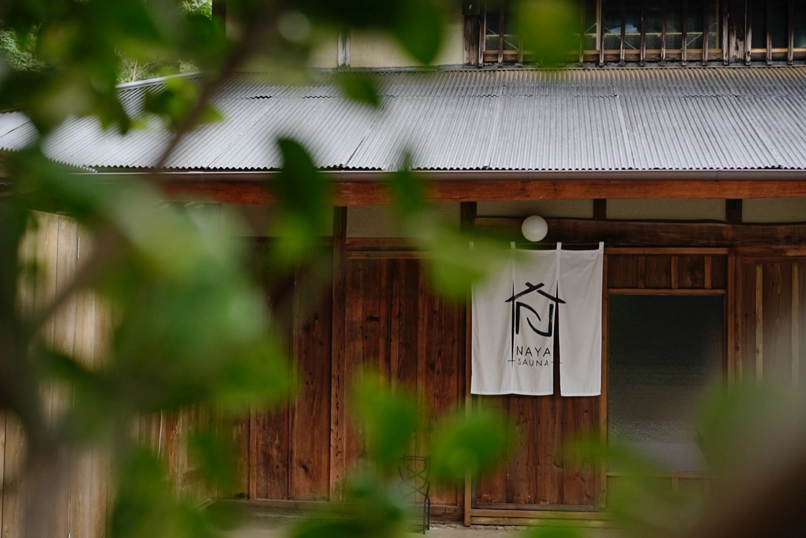 SAUNA NAYAの納屋の外観と屋号ののれん